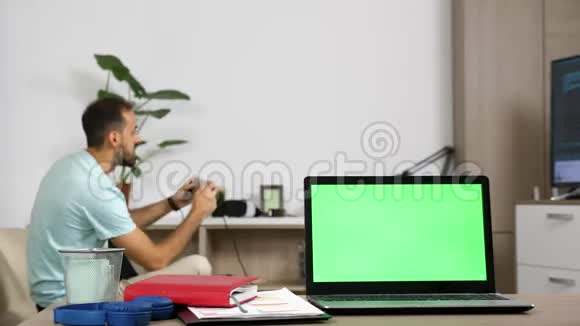 客厅桌子上有绿色屏幕的笔记本电脑视频的预览图