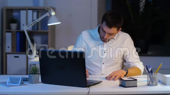 带笔记本电脑和夜间办公室文件的商人视频的预览图