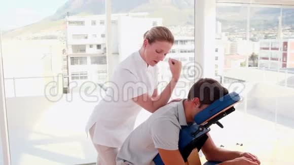 坐在按摩椅上的女性治疗师按摩男视频的预览图