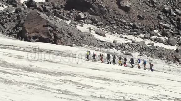 徒步旅行团在山间山谷的雪地上行走雪山峰视频的预览图