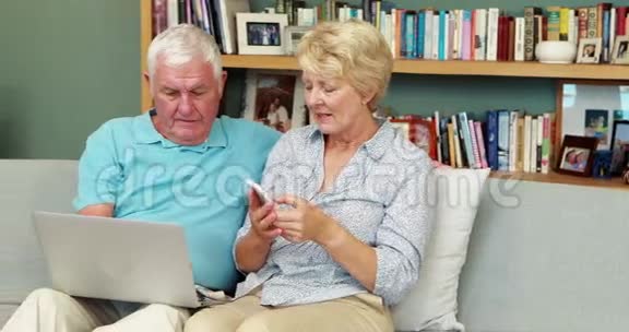 年长夫妇使用笔记本电脑和智能手机视频的预览图