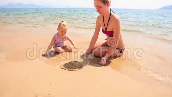 母亲小女儿在蔚蓝海滩玩沙视频的预览图