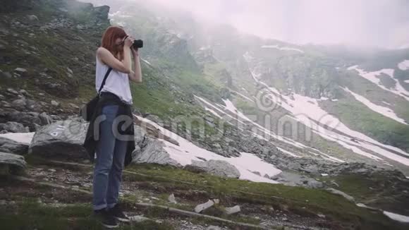 一个年轻的女徒步旅行者带着照片相机爬山罗马尼亚喀尔巴阡山脉视频的预览图