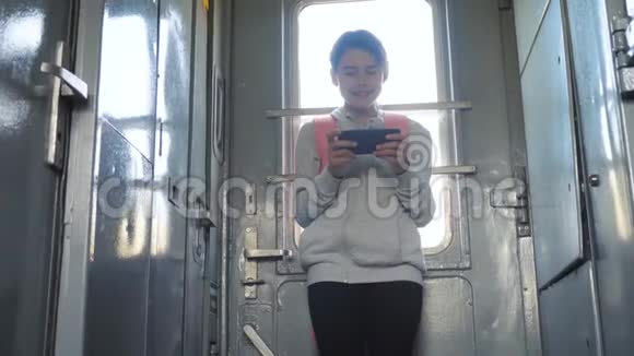 带背包的少女旅行者站在火车的窗户边手里拿着一部智能手机旅行交通视频的预览图