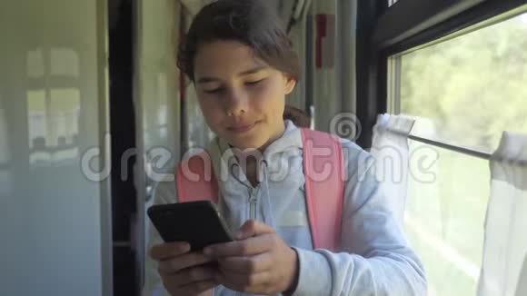 背着背包的少女旅行者拿着一部智能手机站在火车车窗边旅游生活方式视频的预览图