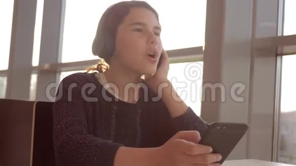 快乐的年轻少女耳机生活方式唱歌和听音乐智能手机社会中的少女视频的预览图