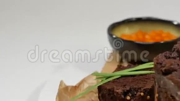 黄油丁鱼子酱黑面包一碗红鱼子酱配勺子配白面包片黄油和香草视频的预览图
