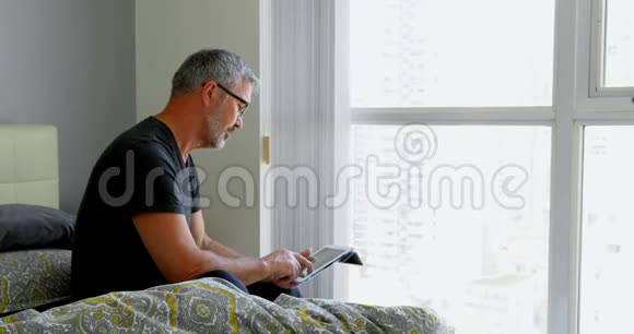 男人在家里床上用数码平板电脑视频的预览图