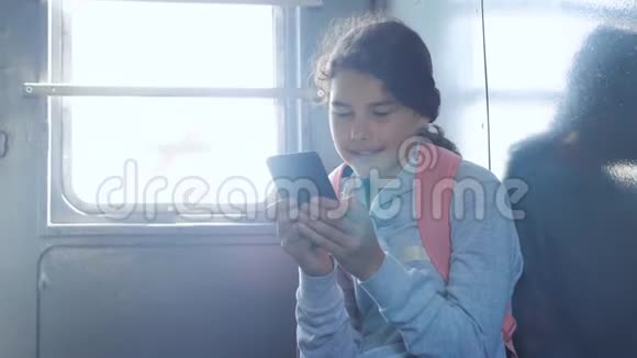 年轻的女孩旅行者带着一个背包坐在装有智能手机的车窗上的背包上旅游线路视频的预览图