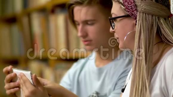 漂亮的女孩和一个年轻人在图书馆视频的预览图