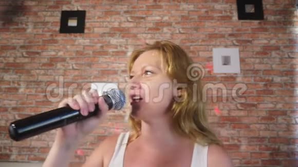快关门一个女人对着麦克风尖叫一个女人在家里把卡拉OK唱成麦克风4k慢动作视频的预览图
