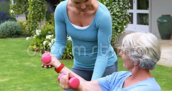 协助老年妇女进行锻炼的女教练视频的预览图