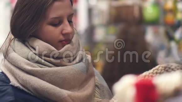 商店里的一个年轻女子选择暖和的冬衣视频的预览图