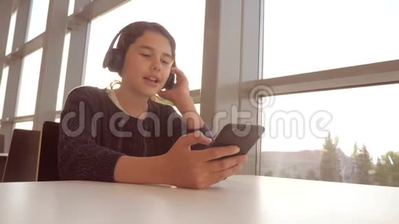 年轻快乐的十几岁女孩戴着耳机唱歌听着智能手机上的音乐社会生活方式青少年女孩视频的预览图