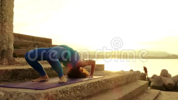 日落时分在海滩上练习瑜伽的女人视频的预览图
