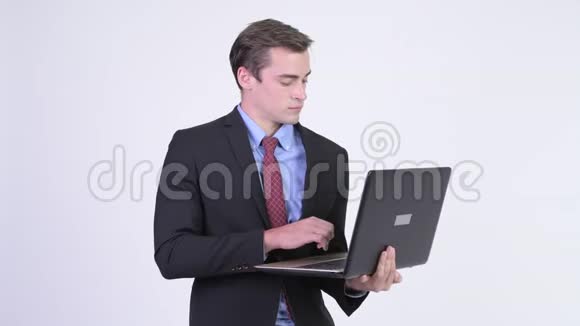年轻快乐的英俊商人在用笔记本电脑思考视频的预览图