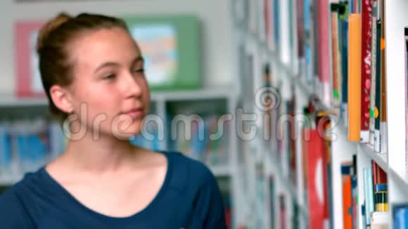 从图书馆书架上挑选书的女生视频的预览图