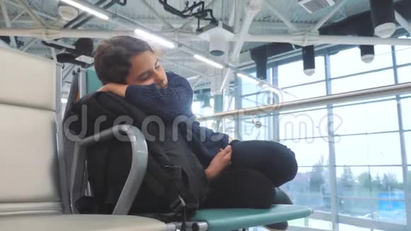 疲惫的少女少年旅行者睡在机场等待飞机起飞登机口的长椅上充满了她的生活方式视频的预览图