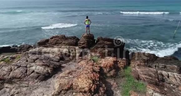 女人在海边的悬崖边张开双臂视频的预览图