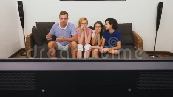 迷人的家庭妈妈爸爸女儿和儿子一起在客厅看电视视频的预览图