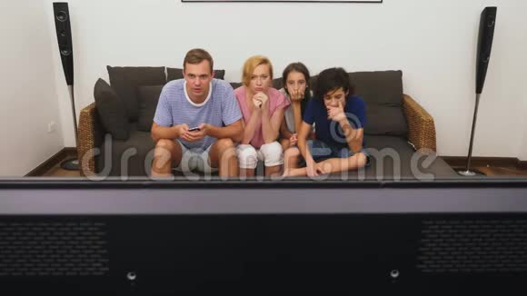 迷人的家庭妈妈爸爸女儿和儿子一起在客厅看电视视频的预览图