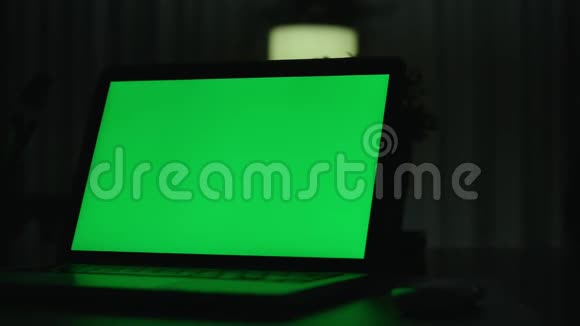 带有绿色屏幕的笔记本电脑黑暗的办公室视频的预览图