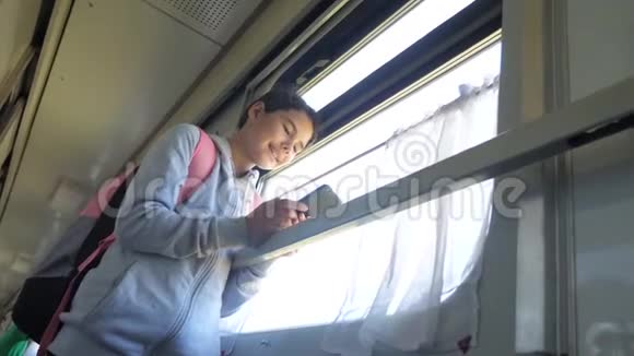 带背包的少女旅行者站在火车车窗旁手里拿着智能手机旅费视频的预览图