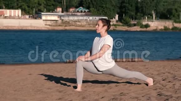 女人在城市河边的海滩上伸展瑜伽美丽的景色视频的预览图