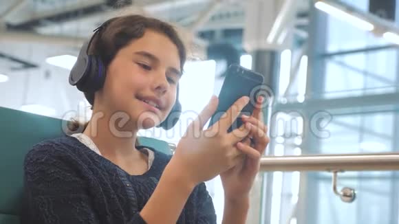 机场候机大厅供飞机飞行年轻快乐的少女耳机听生活方式音乐视频的预览图
