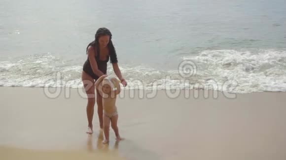 妈妈和一个两岁的女儿在沙滩上散步视频的预览图