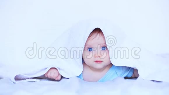 一个蓝眼睛的小男孩躺在白色的床上视频的预览图