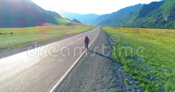 乘坐搭便车游客在沥青路上行走夏日的乡村山谷背包徒步旅行者视频的预览图