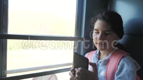 带背包的少女旅行者站在装有智能手机的火车车窗旁旅费视频的预览图
