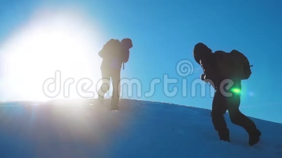 团队合作商务冬季旅行男游客攀登山顶岩石峰团队阳光剪影视频的预览图