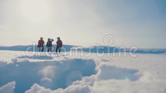 团队合作参考译文参考译文登山者攀登山顶山石峰群团队阳光的剪影雪脚冬天视频的预览图