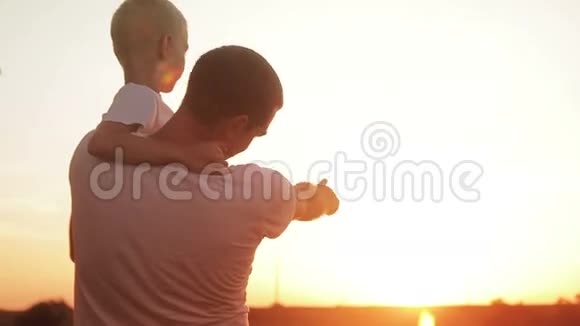父亲和儿子在田野里享受日落的乐趣视频的预览图