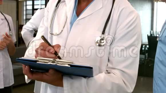 医生在剪贴板上书写的中段视图视频的预览图