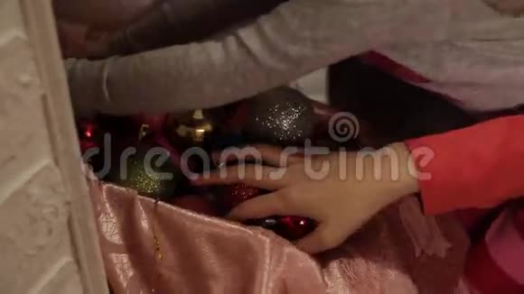 小女孩穿着漂亮的圣诞装饰品坐在地板上两个姐妹用杉木装饰圣诞树视频的预览图