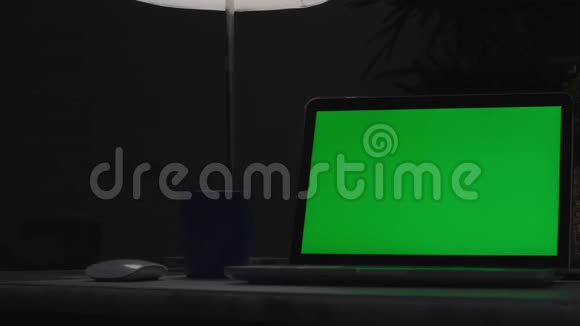 带有绿色屏幕的笔记本电脑黑暗的办公室视频的预览图