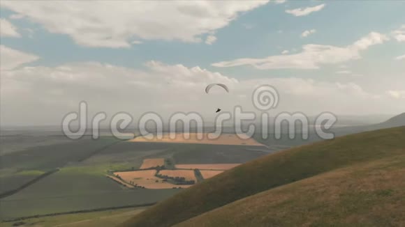 运动员滑翔伞飞行在他的滑翔伞旁边的燕子无人驾驶飞机的后续射击视频的预览图