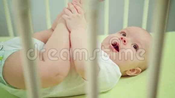 婴儿躺在婴儿床上吃脚和手指视频的预览图