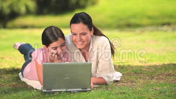 女人和女儿在户外使用笔记本电脑视频的预览图