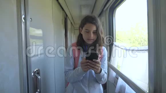 十几岁的女孩带着背包和智能手机在火车车厢里散步旅游运输铁路概念a视频的预览图