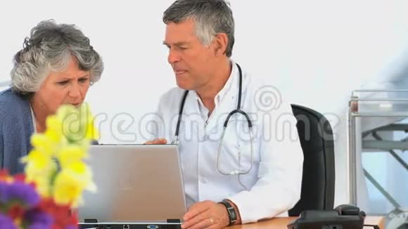 医生带着病人看着笔记本电脑视频的预览图