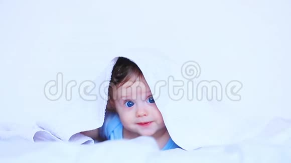一个蓝眼睛的小男孩躺在白色的床上视频的预览图