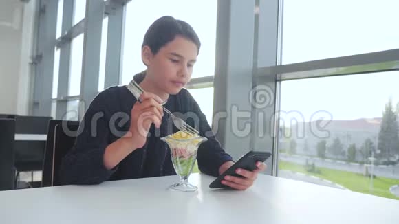 机场等待飞机航班十几岁的女孩吃沙拉看上去像智能手机在咖啡馆里上网机场航站楼视频的预览图
