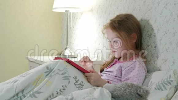 在床上玩平板电脑的小女孩视频的预览图
