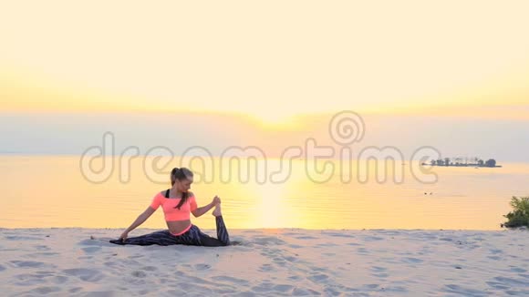 健康的年轻美女日出时在海边打坐伸展身体练习瑜伽视频的预览图