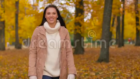秋天公园散步的快乐年轻女子视频的预览图