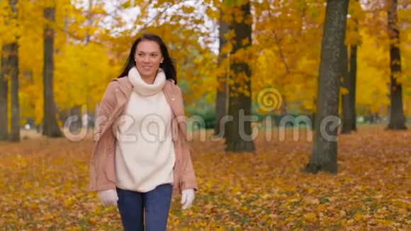 秋天公园散步的快乐年轻女子视频的预览图